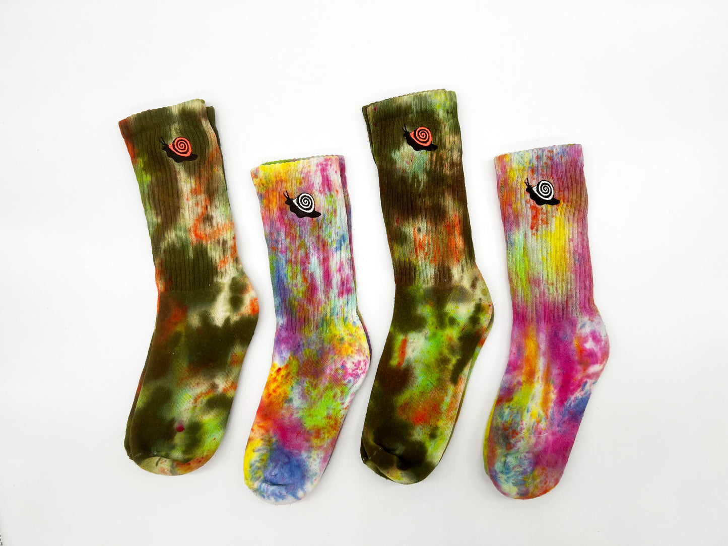 Two different styles of hand dyed and embroidered socks, one in greens and oranges called 'Alligator Camo' and one in all colors of the rainbow called 'Party Rainbow'