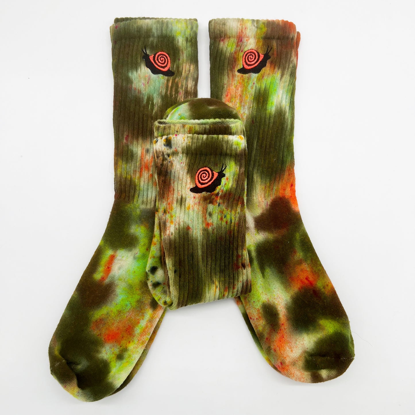 Three pairs of alligator camo dyed socks with orange and black embroidered spiral snail